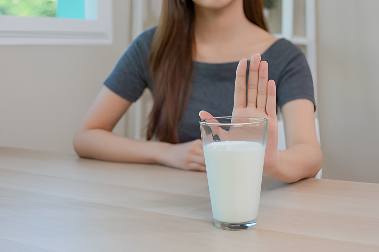 woman doing the stop hand gesture against a glass of milk