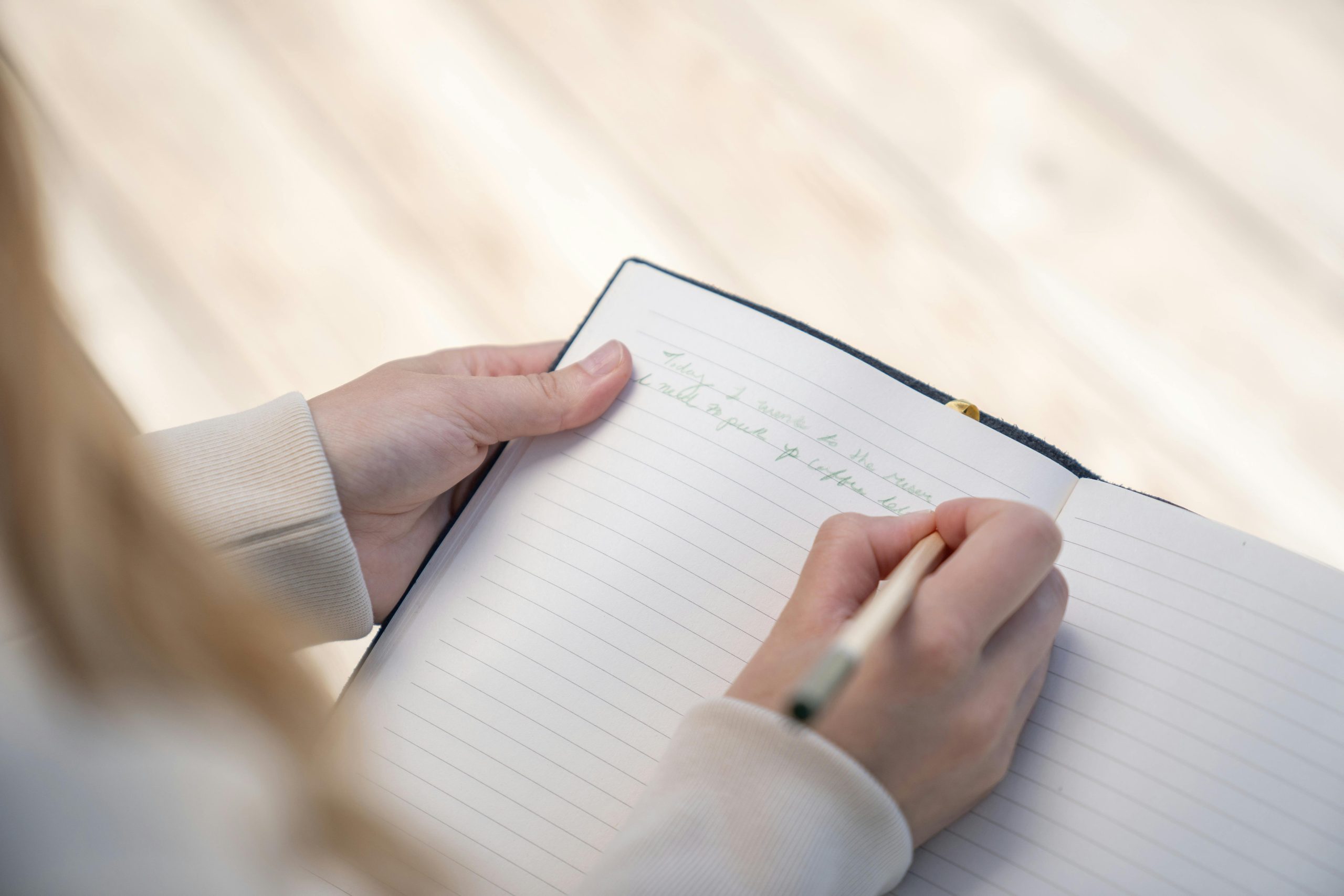 woman in a white sweater writing on a journal