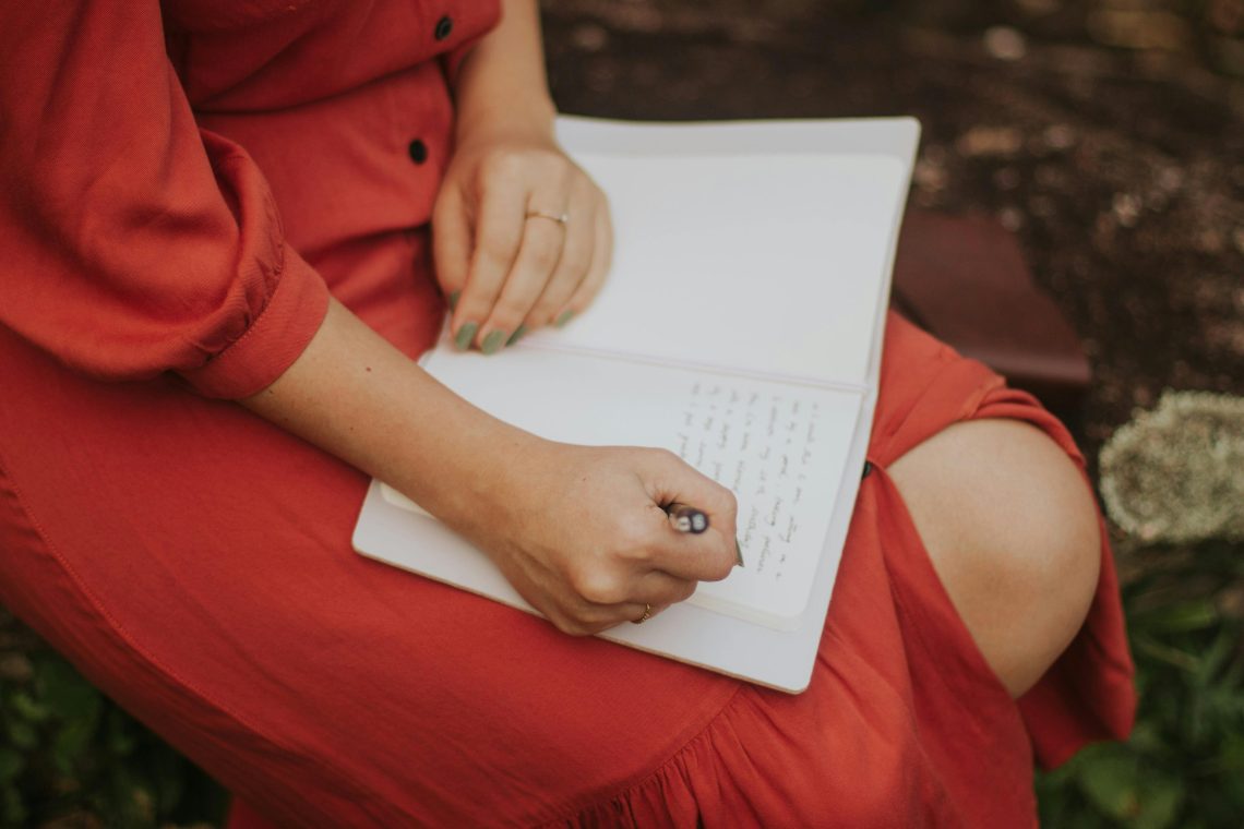woman in a red dress journaling outdoors