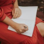 woman in a red dress journaling outdoors