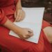 woman in a red dress journaling outdoors